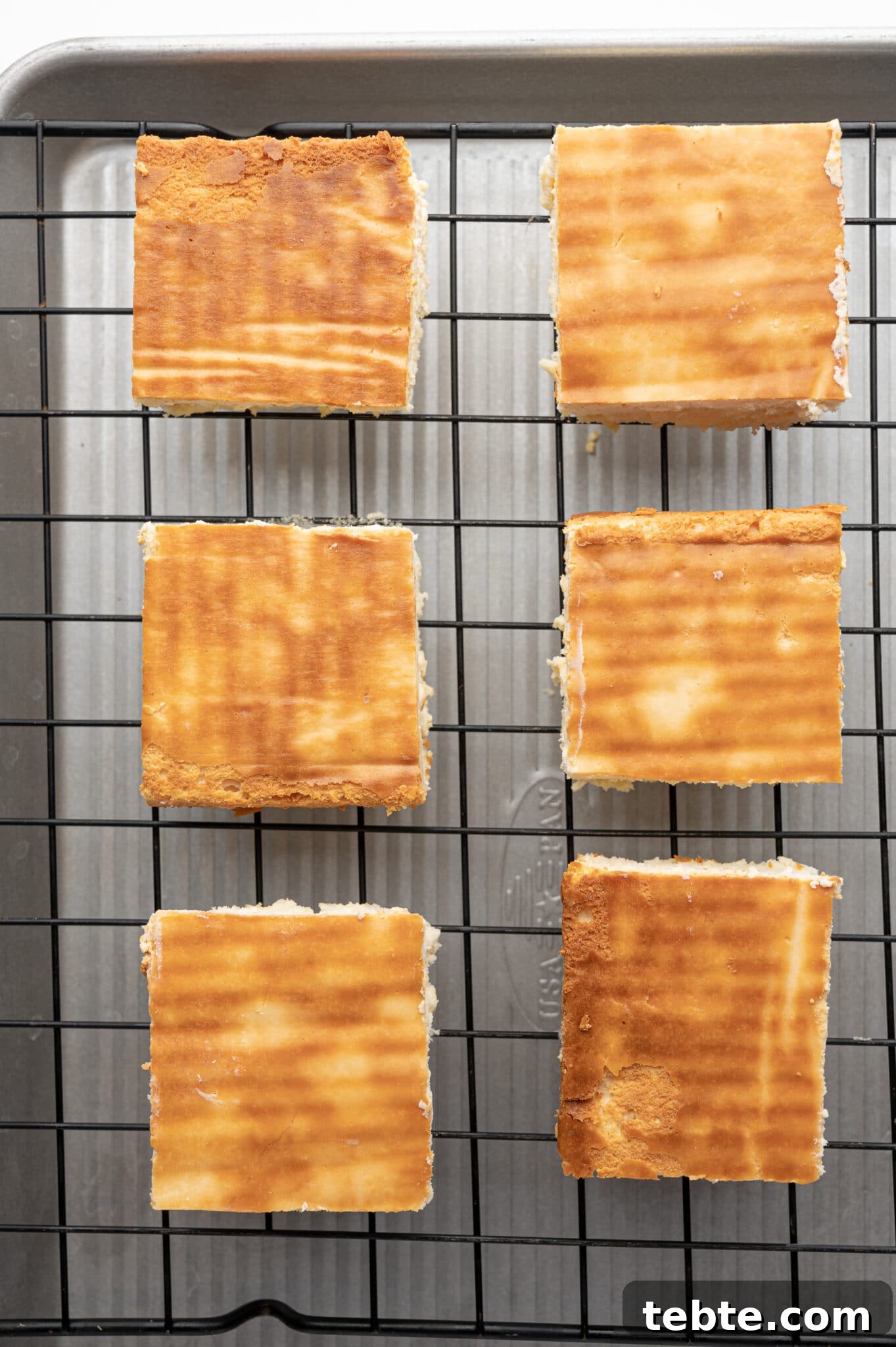 Cute square of baked cheesecake on a cooling rack