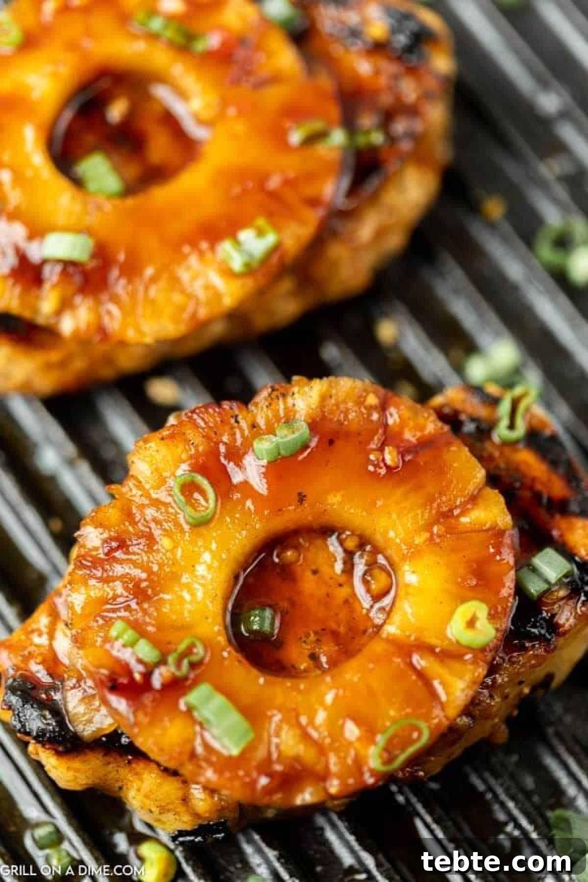 Hawaiian-Style Grilled Pork Chops with Pineapple Glaze 10 Grilled pork chops topped with caramelized pineapple rings and sprinkled with chopped green onions, served on a grill pan.