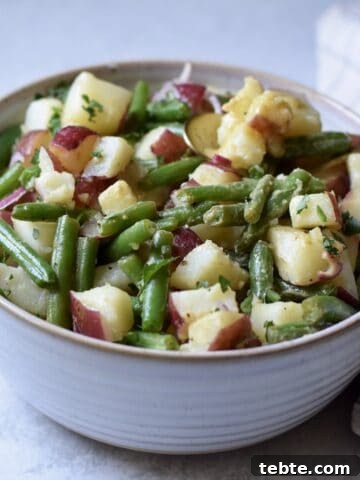 A large bowl of green beans and potato salad, perfect for feeding a crowd.