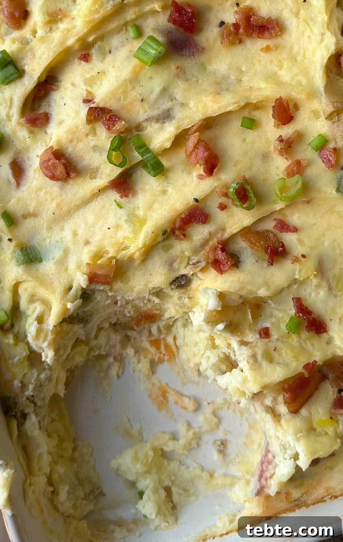 Twice-Baked Potato Casserole: Loaded Mashed Potato Bake 10 A casserole dish of cheese and bacon mashed potatoes with one portion scooped out.
