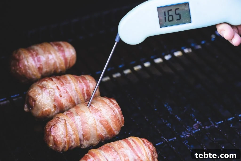 Smoky Bacon-Wrapped Armadillo Eggs: Juicy Jalapeño Poppers with Cream Cheese 5 Armadillo eggs on the smoker with an internal thermometer reading 165 degrees F.