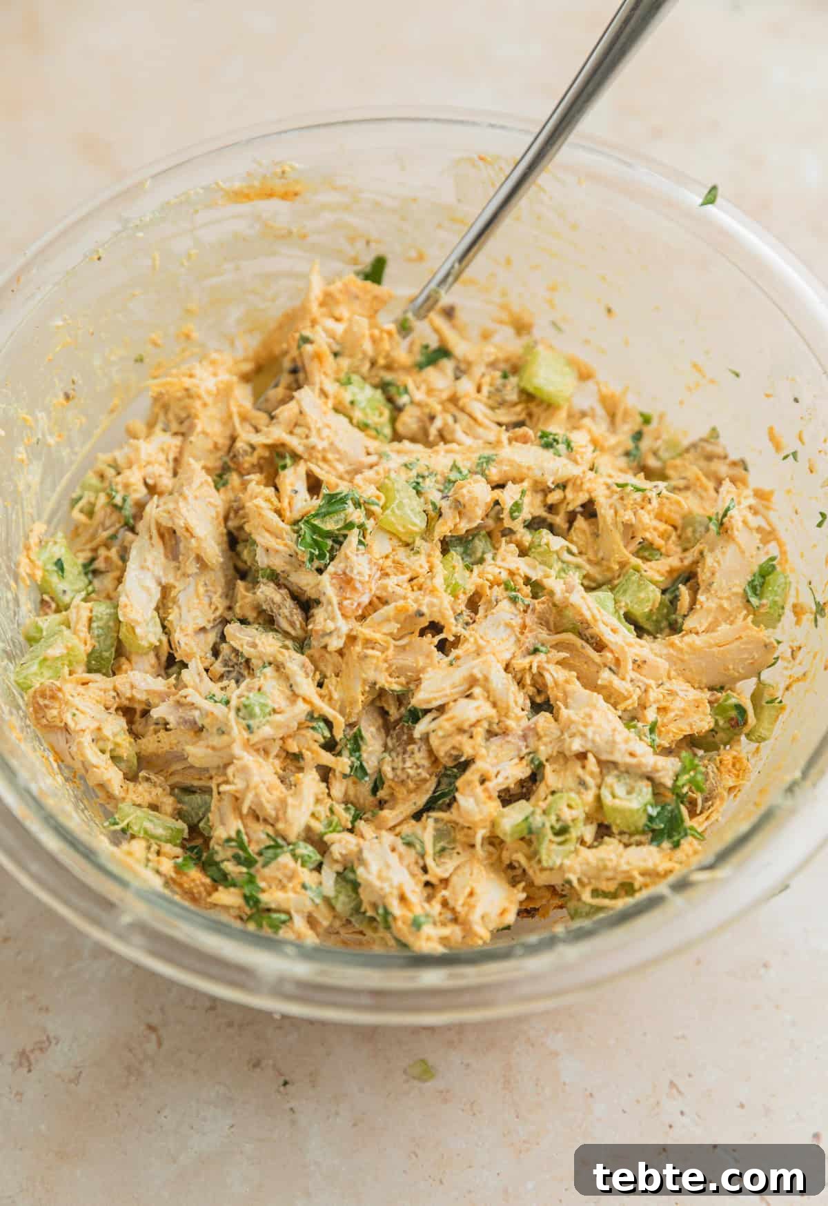 Creamy Curry Chicken Salad Recipe with Crunchy Apples and Almonds 5 Mixed curry chicken salad in glass mixing bowl with spoon.