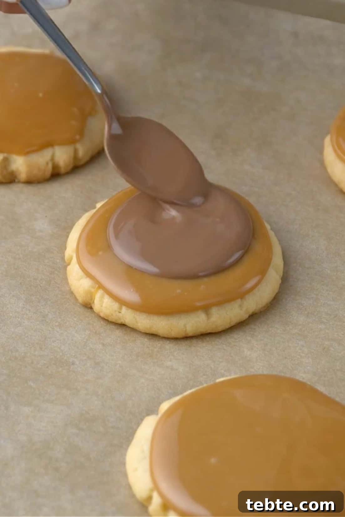 melted chocolate being placed on caramel for twic cookies.