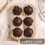 Six double chocolate banana muffins with mini chocolate chips in a muffin tin.