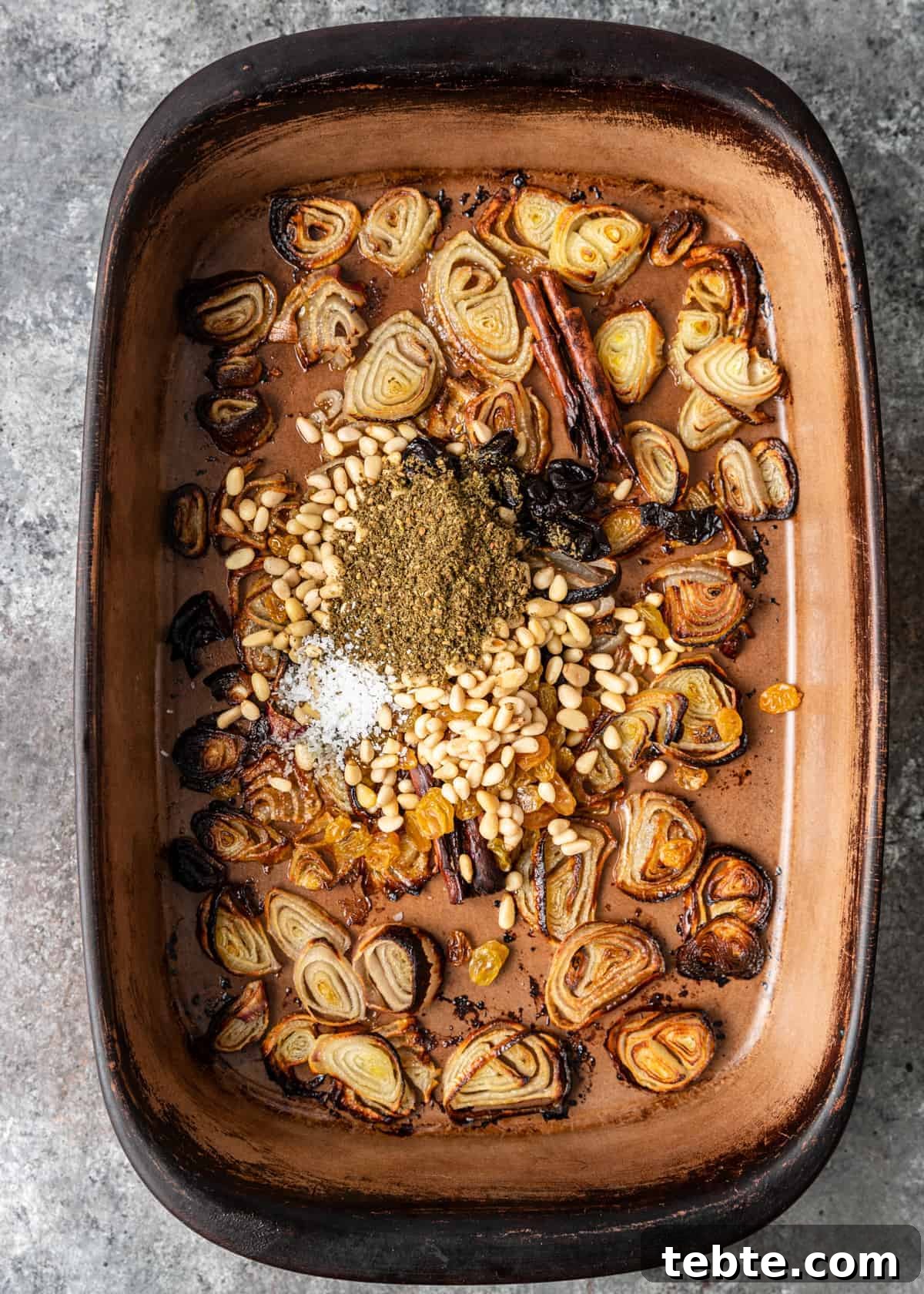Authentic Middle Eastern Rice Pilaf Recipe with Aromatic Spices 6 overhead: layer of Lebanese spices and shallot slices in bottom of casserole dish