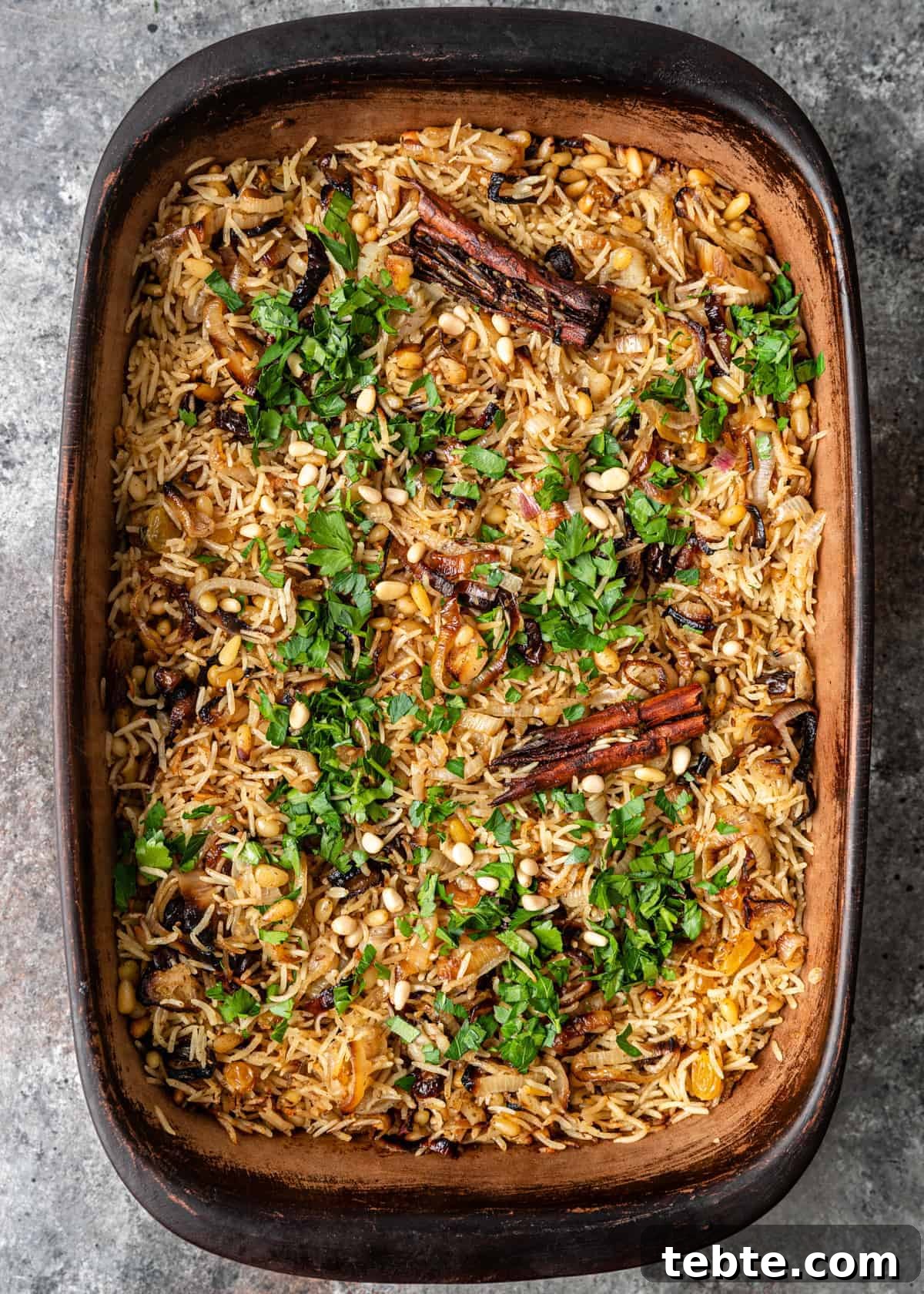 Authentic Middle Eastern Rice Pilaf Recipe with Aromatic Spices 9 overhead: oven baked basmati rice pilaf with dried cherries, golden raisins, pine nuts and cinnamon sticks, with sprinkling of fresh parsley