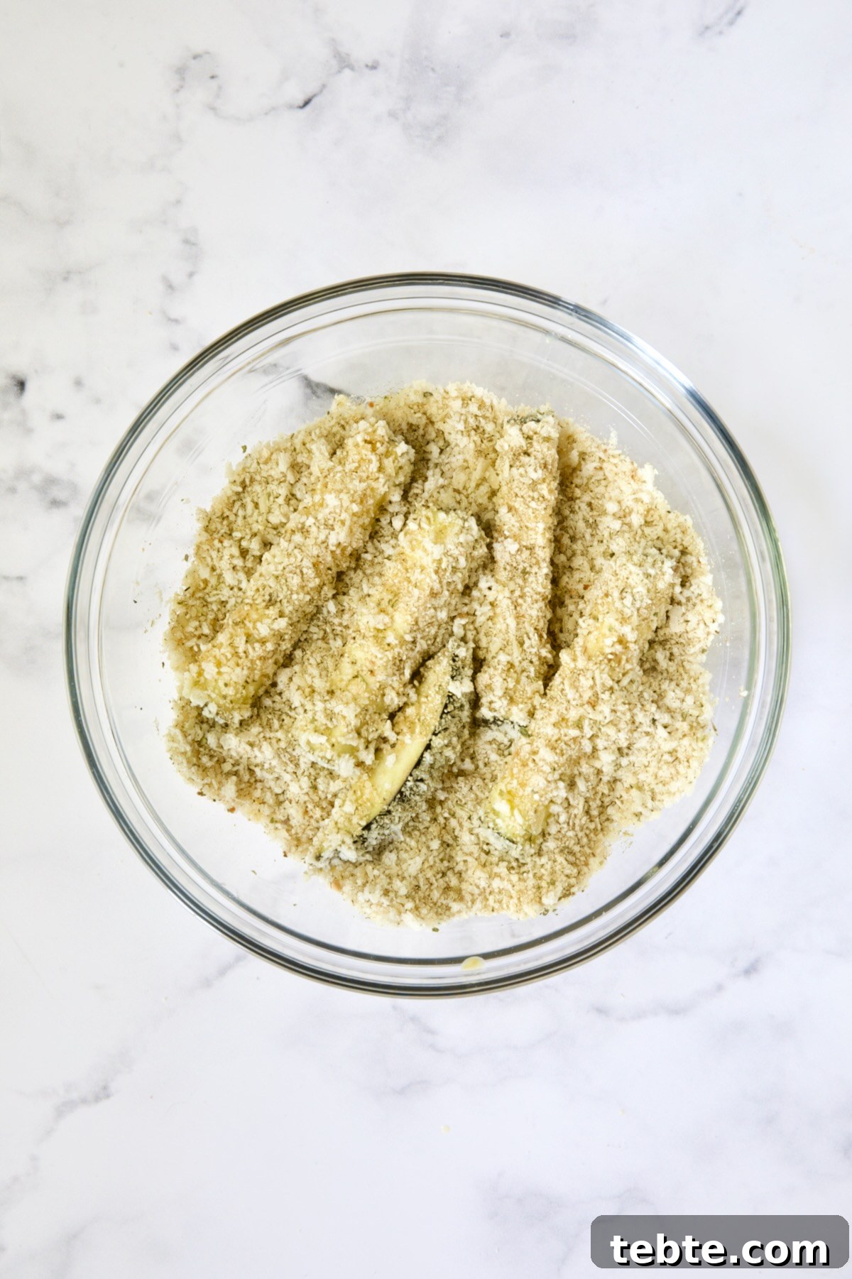 Crispy Air Fryer Eggplant Fries with Garlic Parmesan Dip 13 Eggplant fries in breadcrumb coating in glass bowl.