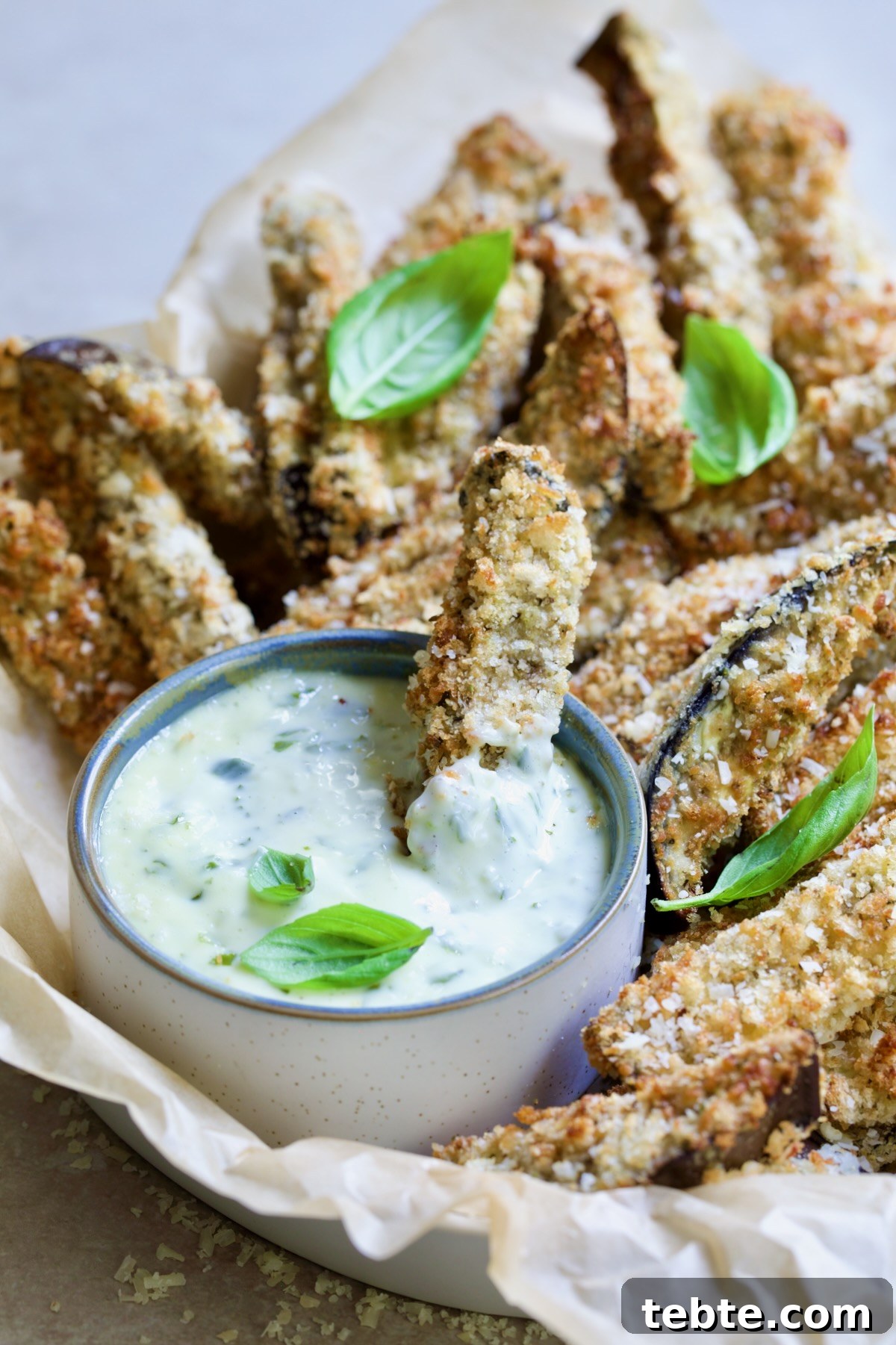 Crispy Air Fryer Eggplant Fries with Garlic Parmesan Dip 18 Eggplant fries in basket with one dipped into Garlic Basil Aioli.
