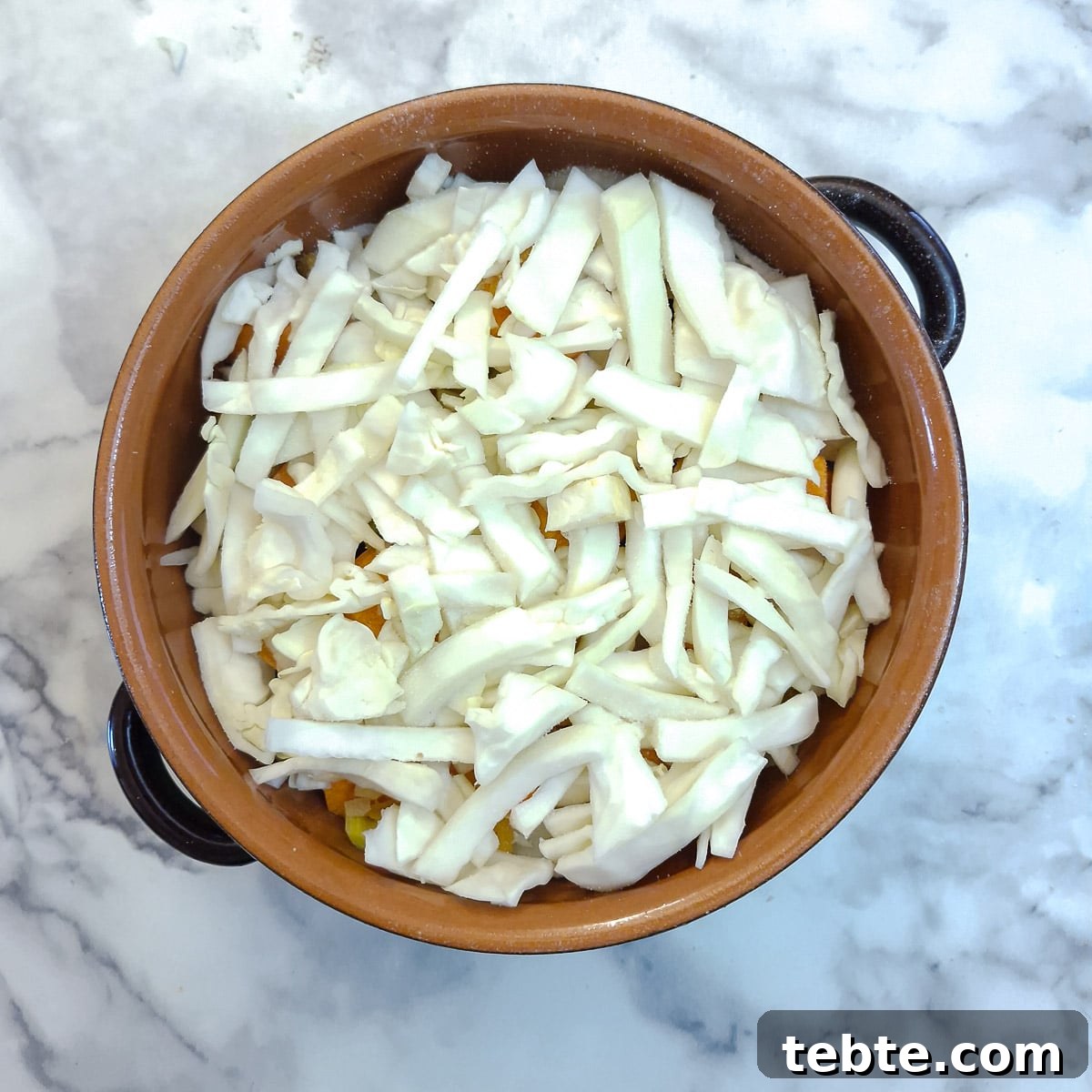 A layer of chopped cabbage on top of the carrots.