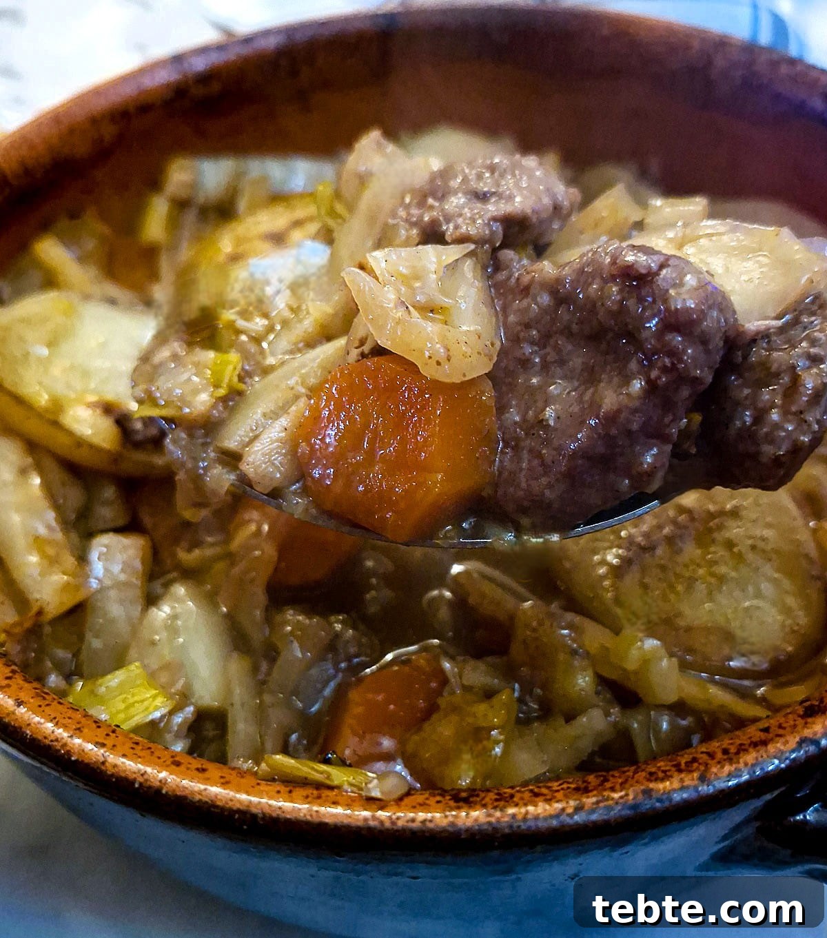 Close up of a spoonful of lamb and vegetables being lifted from the casserole dish.