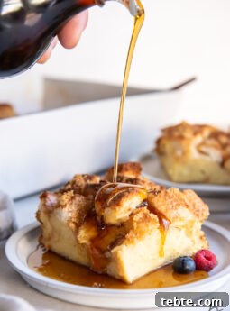 maple syrup being poured over square slice of french toast casserole on round white plate
