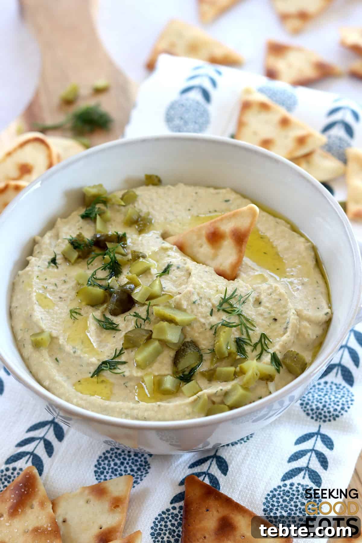 Dill Pickle Hummus: Tangy Chickpea Spread Recipe That Pops 2 Creamy dill pickle hummus served in a white round bowl garnished with diced dill pickles.
