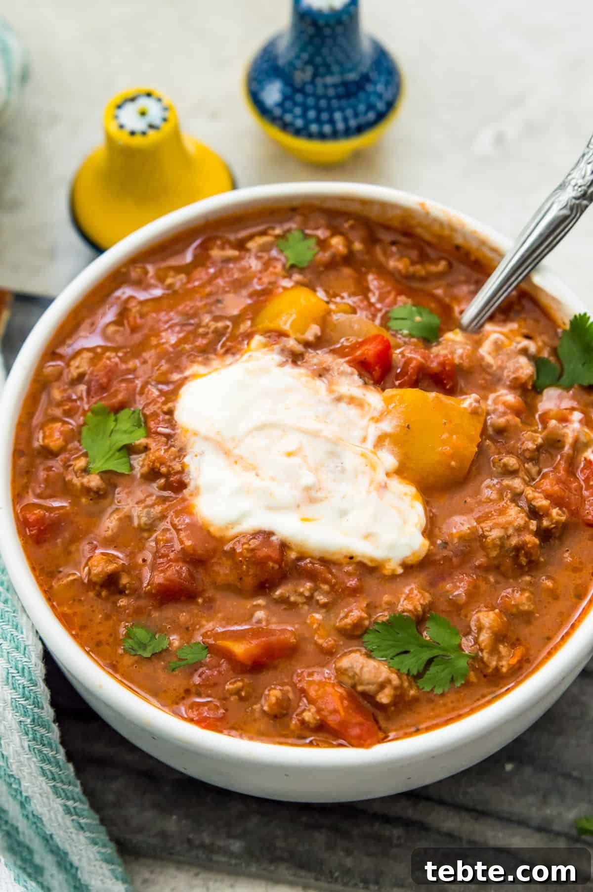 A bowl of chili topped with sour cream and garnished with fresh cilantro.
