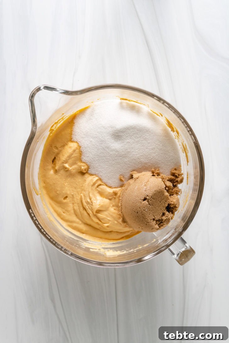 Top down view of sugars on top of pumpkin cream cheese mixture in a bowl.