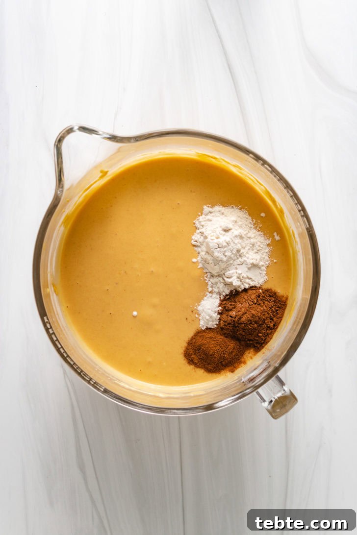 Flour and spices in a bowl with pumpkin cheesecake filling.