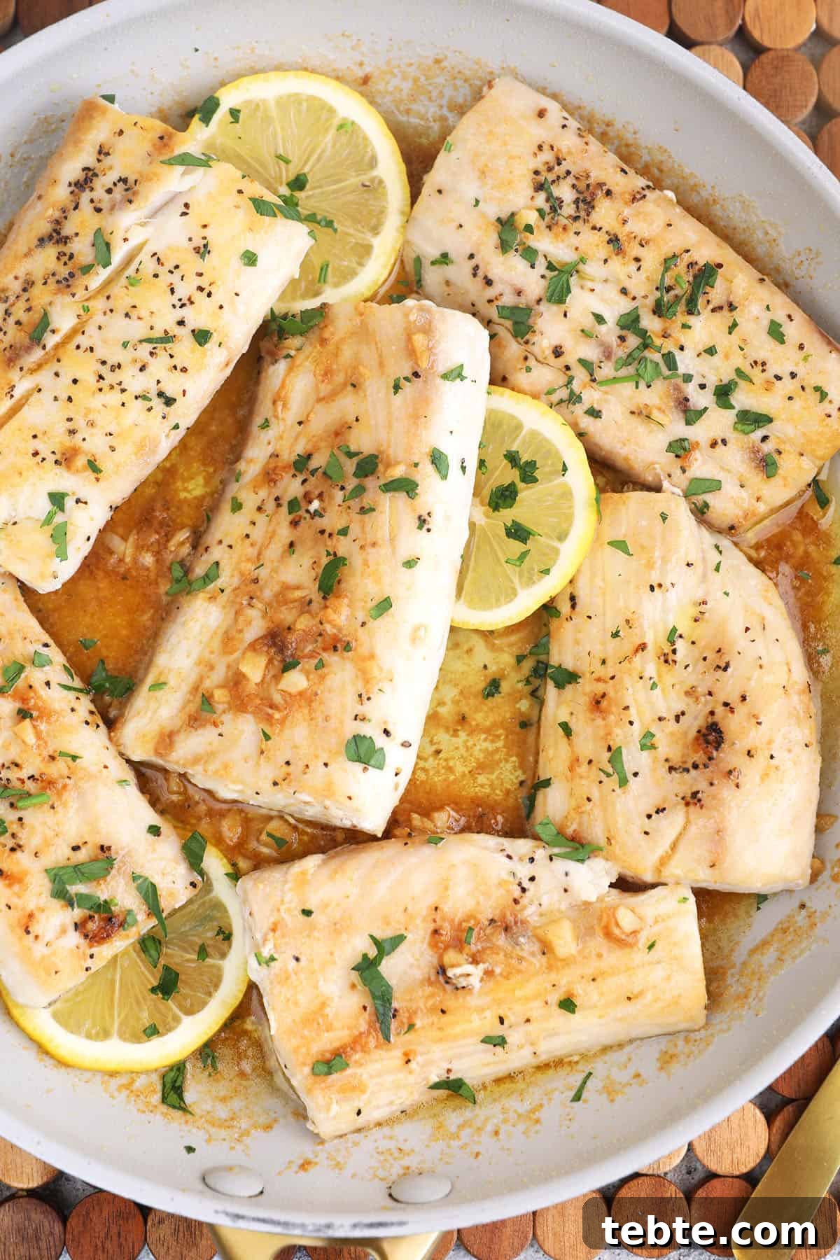 Miso Garlic Butter Mahi Mahi Recipe with Lemon and Herbs 5 Overhead view of mahi mahi with miso garlic butter sauce in skillet with lemon slices