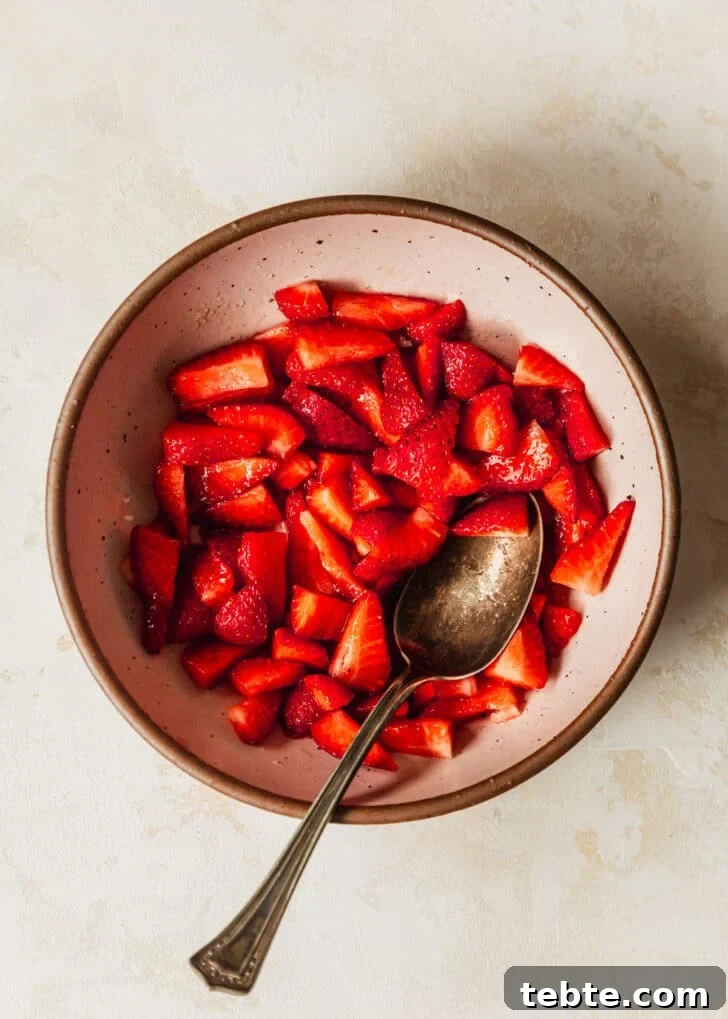 Mini Strawberry Cheesecakes Recipe: Perfect Bite-Sized Treats 16 A pink bowl of strawberry cheesecake topping on a beige counter.