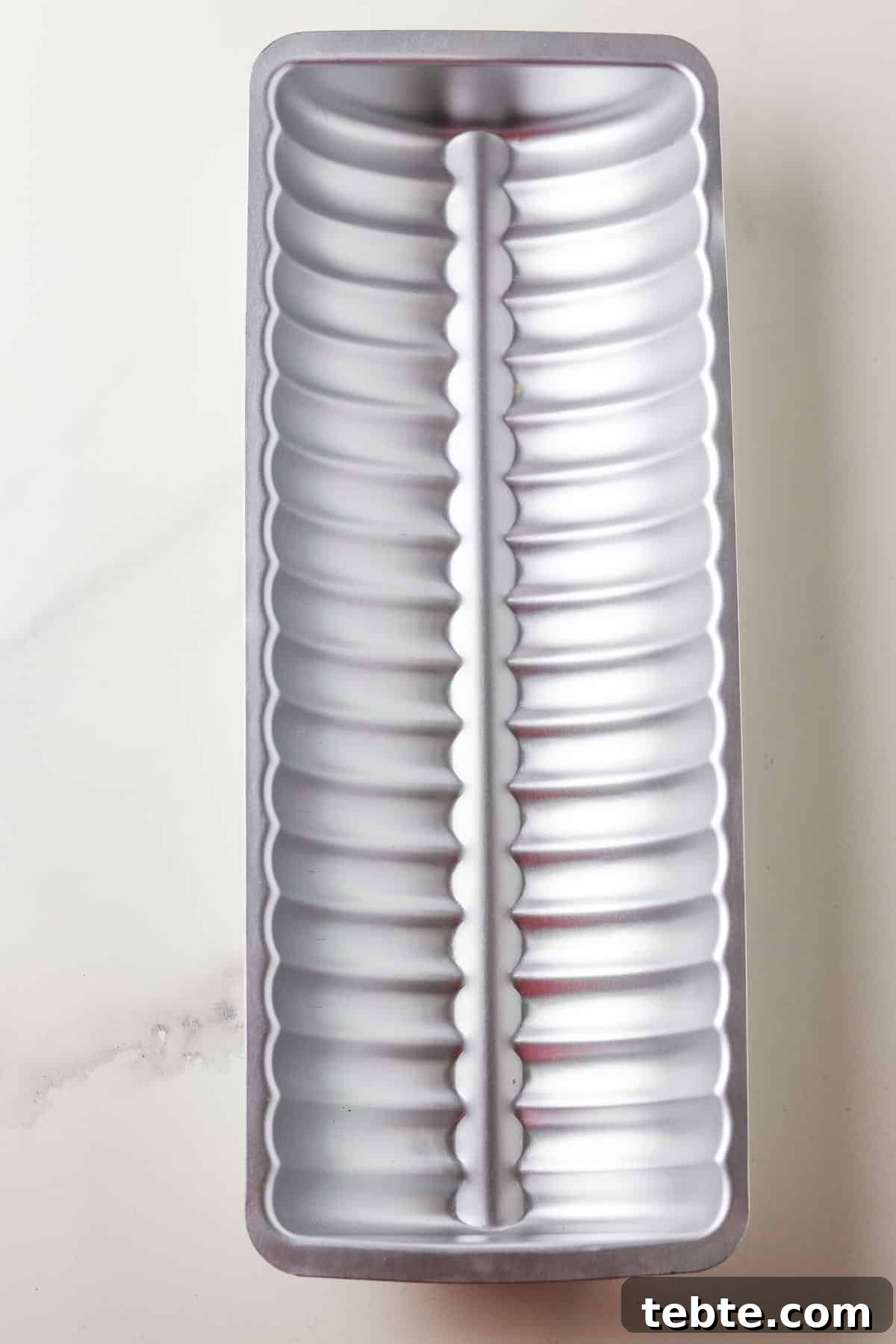 Fluted metal tube pan used for Swedish Spice Cake on a marble surface.