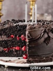 black velvet cake with a piece cut out and black frosting