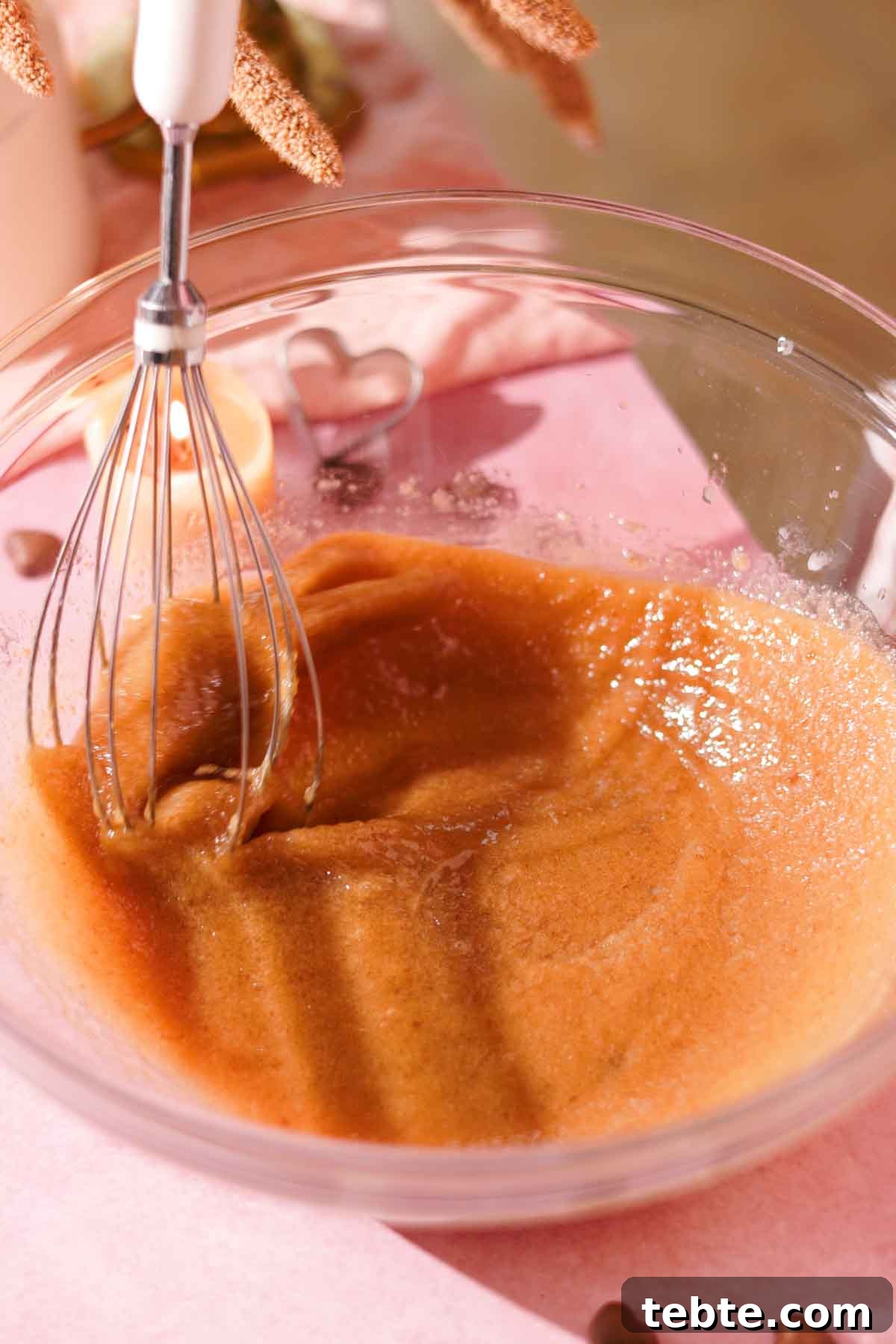 whisking butter and sugar with a wire whisk in a glass bowl