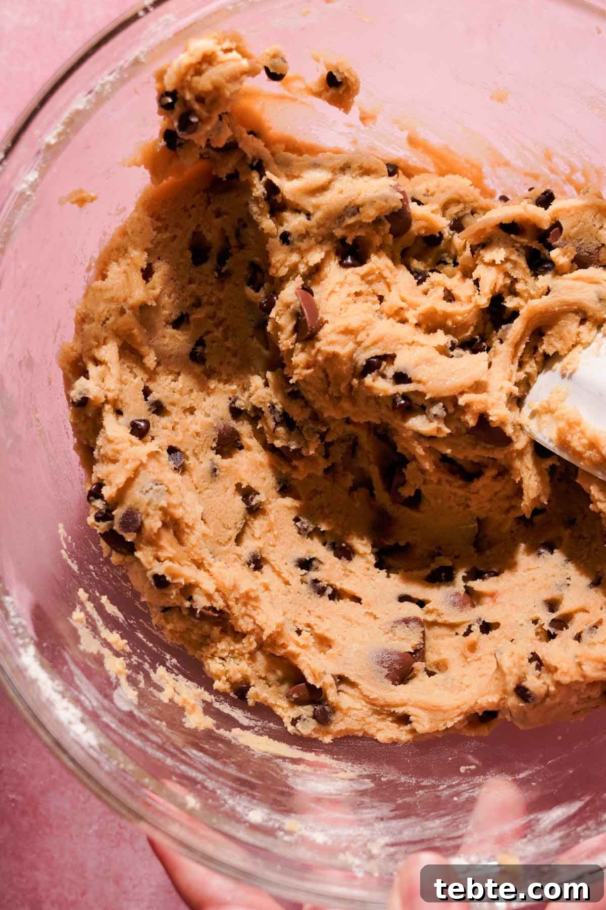 stirring cookie dough with chocolate chips using a silicone spatula