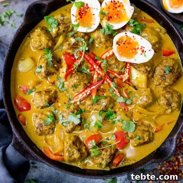 Chinese-Style Beef Curry Recipe: Savory Stir-Fry with Aromatics 12 Meatballs with a Chinese Curry Sauce in a cast iron pan with 3 slices of boiled egg in the top right corner.