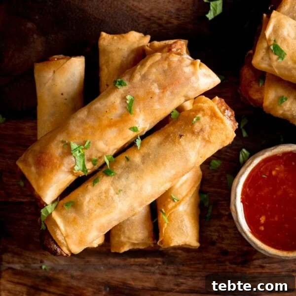 Chinese-Style Beef Curry Recipe: Savory Stir-Fry with Aromatics 8 Overhead picture of a stack of 5 cooked vegetable spring rolls on a wooden board with a small pot of sweet chilli sauce.