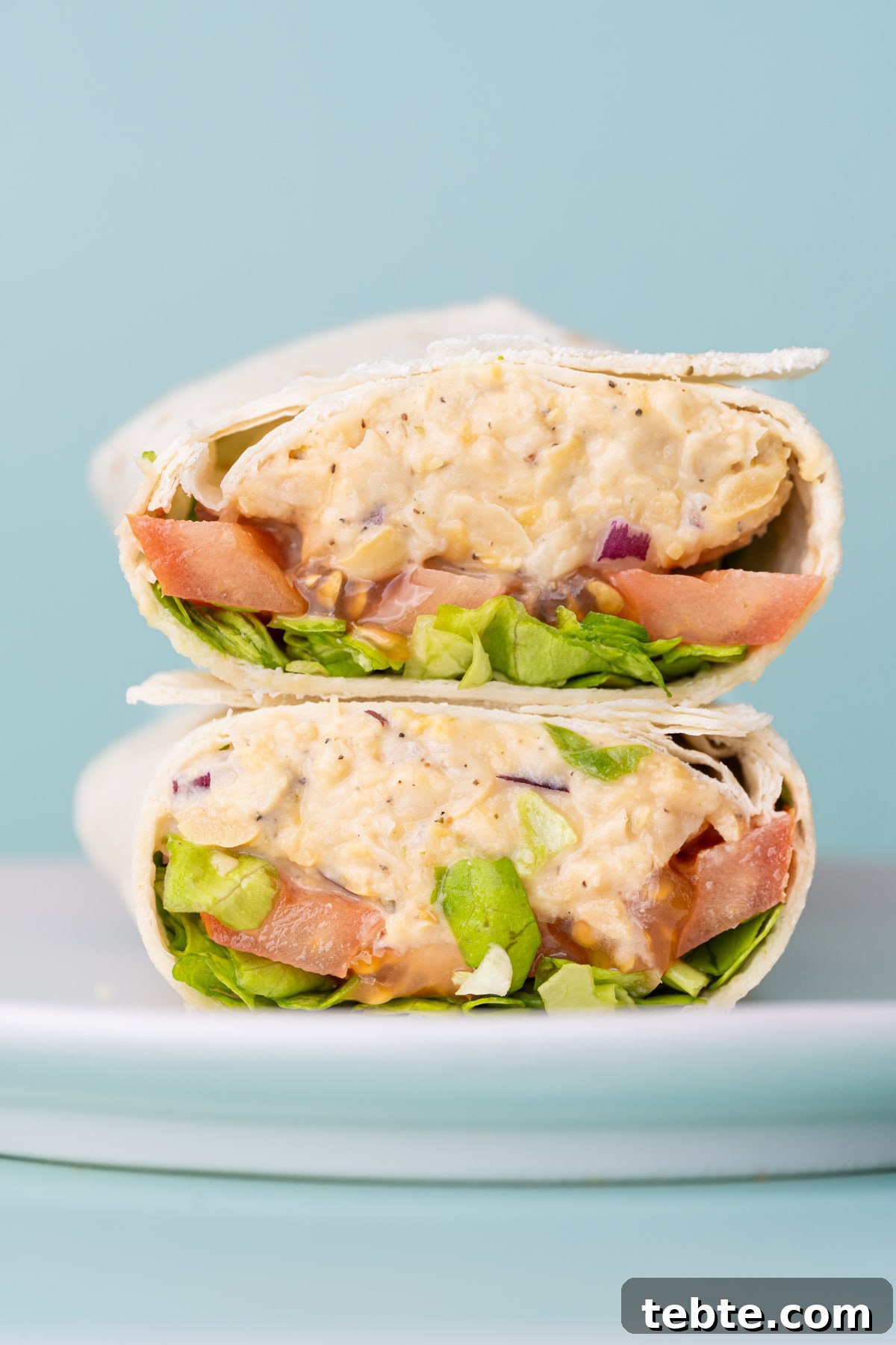 10-Minute Chickpea Salad Wrap Recipe for Quick Lunch 10 Two halves of a quick 5-minute vegetarian lunch wrap stacked on top of each other on a plate.