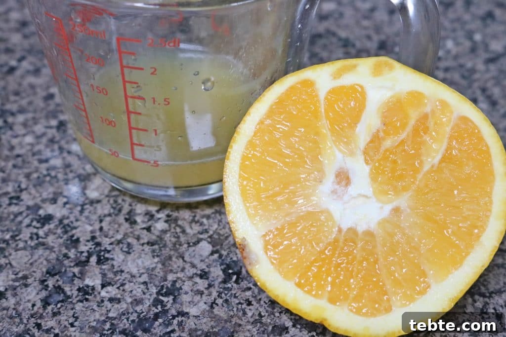 Mango Avocado Smoothie Without Banana — Creamy Tropical Drink 4 Half an orange sitting beside a measuring cup of fresh orange juice