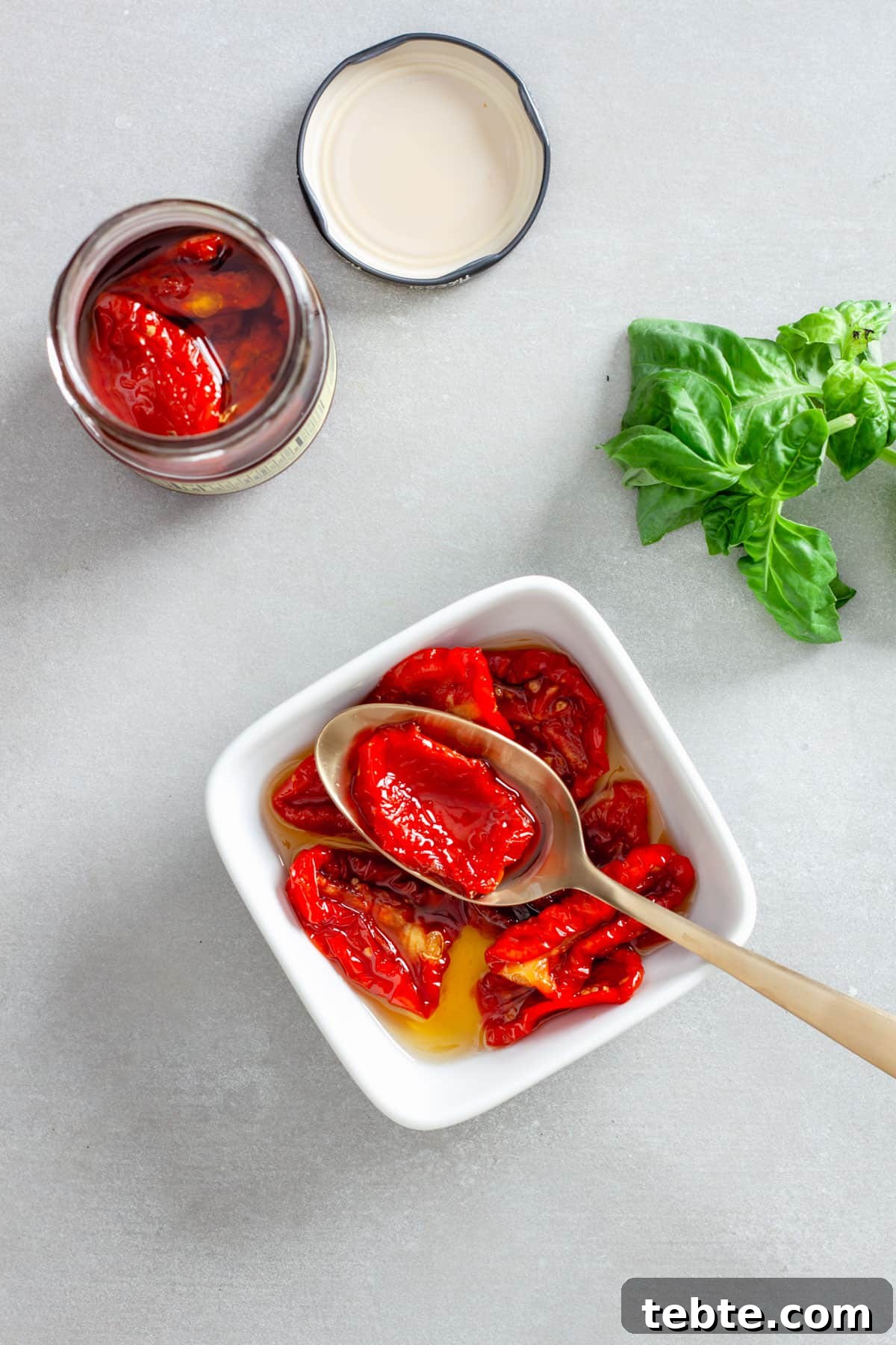 Sun-Dried Tomato Vinaigrette Recipe for Bright, Tangy Salads 4 Whole sun-dried tomatoes in oil in a small white bowl with some basil off to the side.