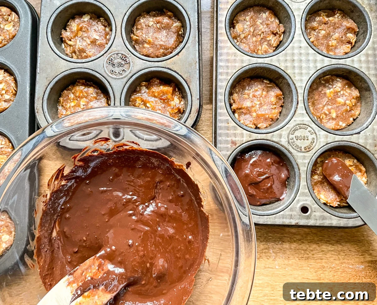 No-Bake Chocolate Almond Oat Cups — Dairy & Gluten Free 7 spreading chocolate topping onto dough in tins