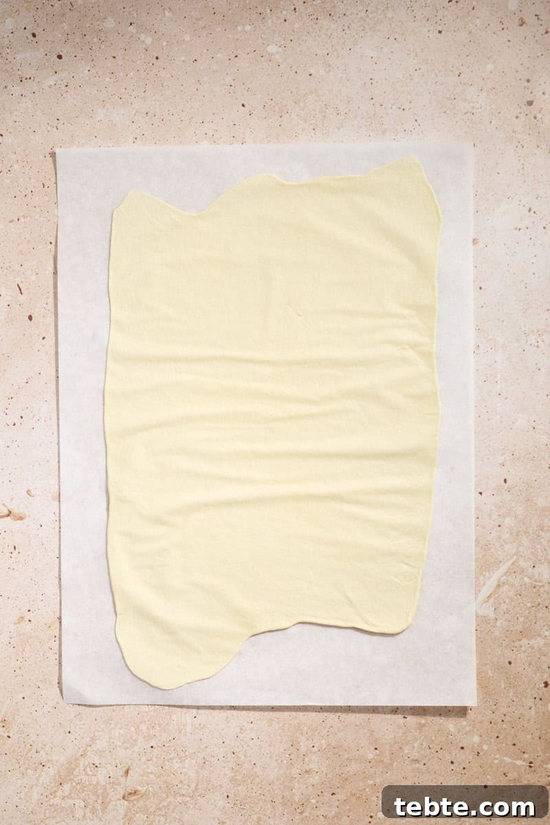 Crispy Sourdough Discard Crackers: Crunchy Homemade Recipe 7 Dough rolled thin on a piece of parchment paper.