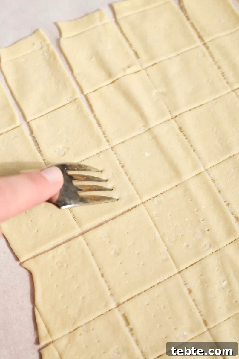 Crispy Sourdough Discard Crackers: Crunchy Homemade Recipe 9 A fork poking holes in the Sourdough Discard Crackers.