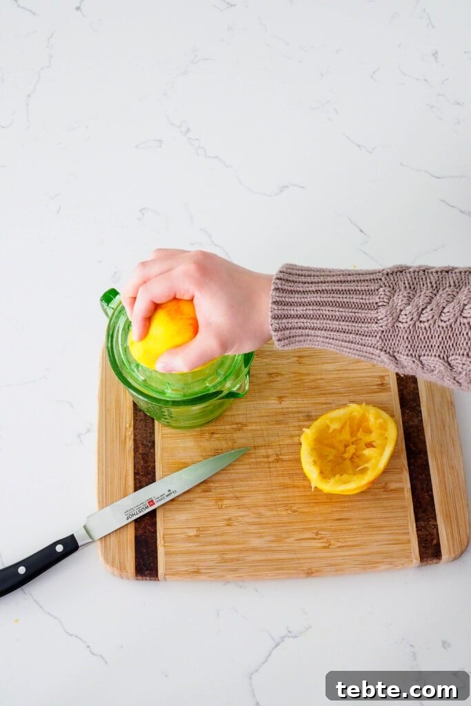 Classic Homemade Cranberry Sauce for Thanksgiving 5 A hand squeezes fresh orange juice.