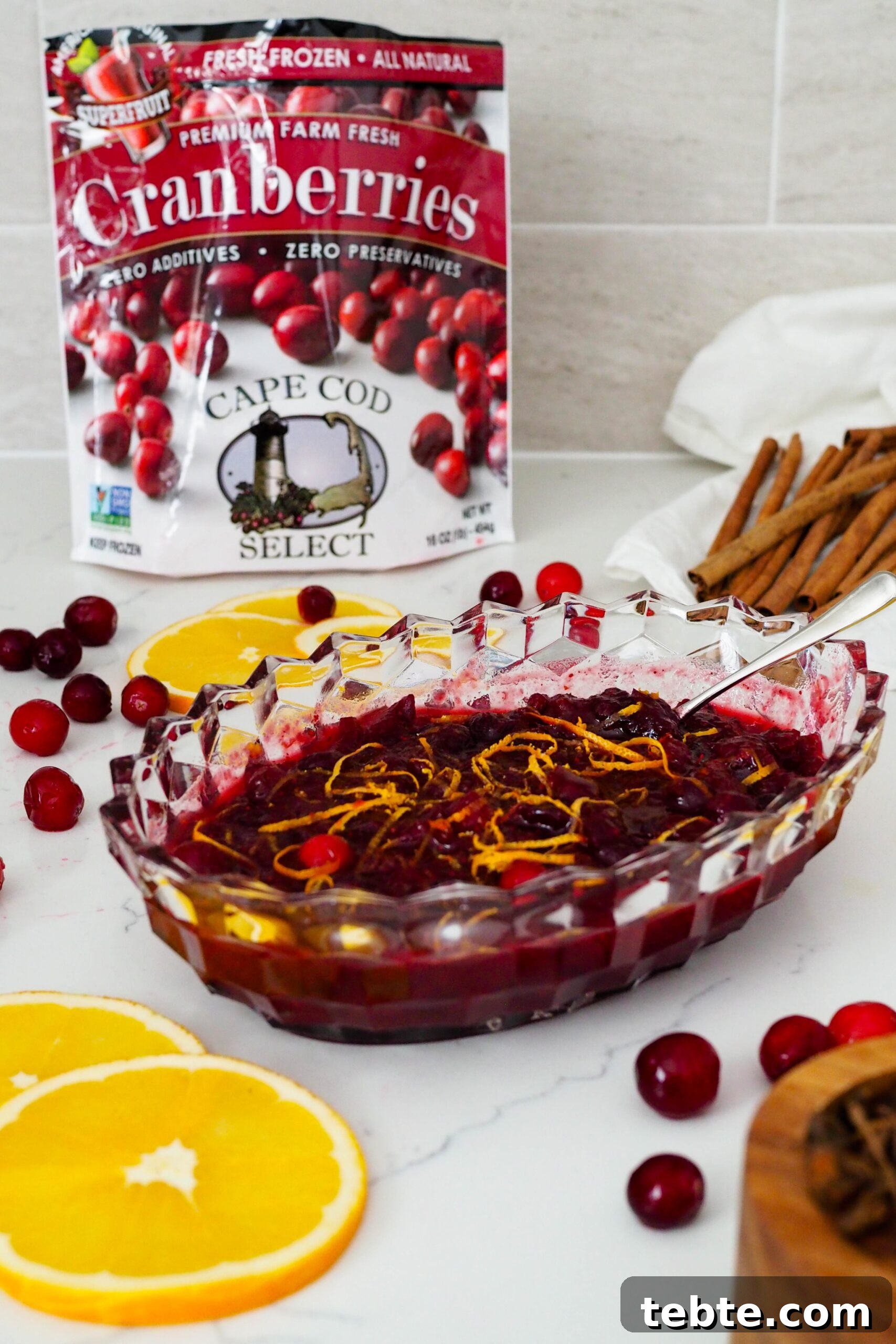 Classic Homemade Cranberry Sauce for Thanksgiving 8 A Cape Cod Select frozen cranberries bag in the background of a crystal dish full of cranberry orange sauce.