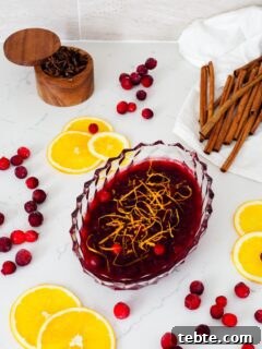 Classic Homemade Cranberry Sauce for Thanksgiving 10 Cranberry orange sauce on a quartz counter with orange slices and cranberries around it.