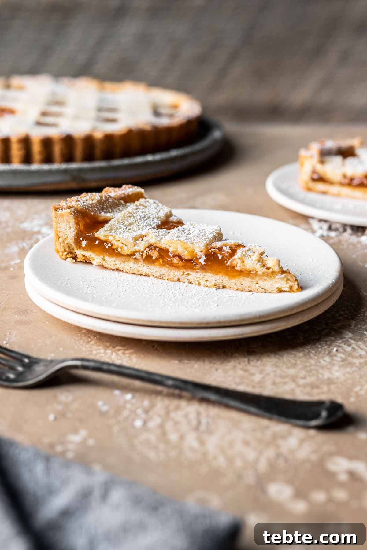 Classic Italian Jam Tart (Crostata) Recipe 16 A slice of lattice topped apricot jam tart on a plate.