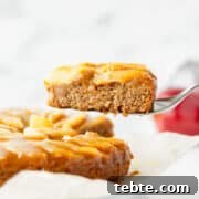Moist Vegan Apple Cake Recipe with Cinnamon and Maple Glaze 6 A slice of vegan apple cake being lifted up.