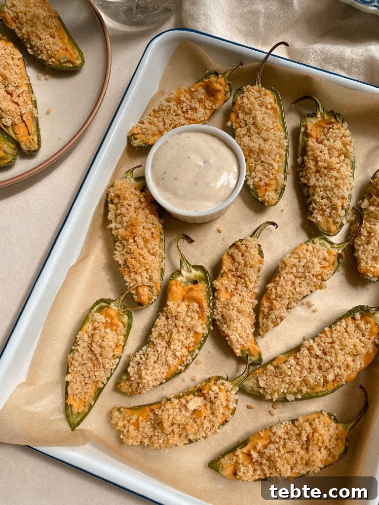 Gluten-Free Vegan Jalapeño Poppers: Creamy Dairy-Free Appetizer 4 jalapeno poopers with small bowl of ranch on parchmenet paper