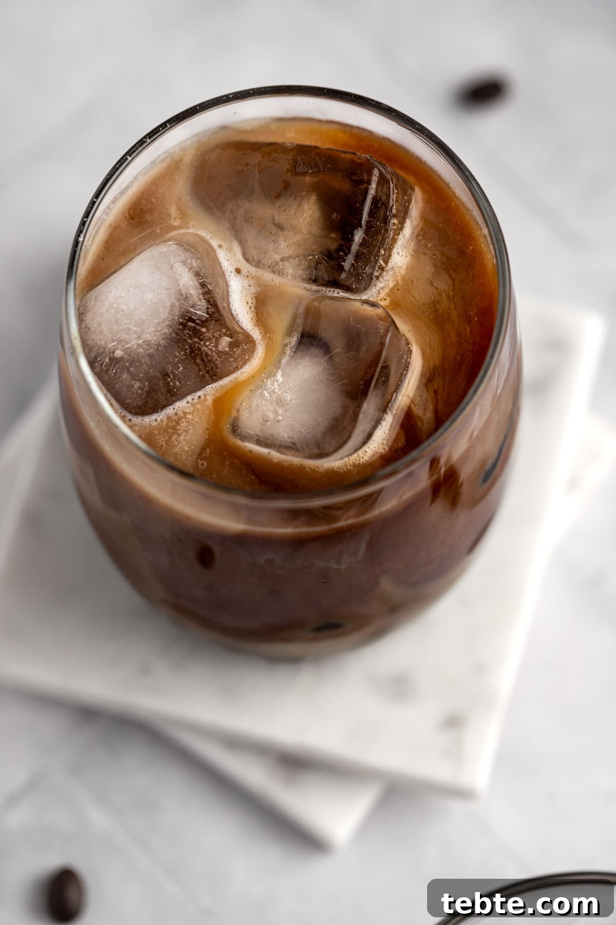 Protein Iced Coffee Recipe: High-Protein Chilled Coffee Drink 8 A glass of protein coffee with ice cubes on a white marble table.