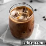 Overhead view of a glass of protein iced coffee sitting on two square white marble coasters.