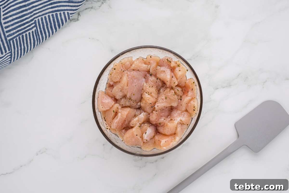 Creamy Chicken and Artichoke Sliders: Savory Party Bites 4 raw seasoned chicken in glass bowl.