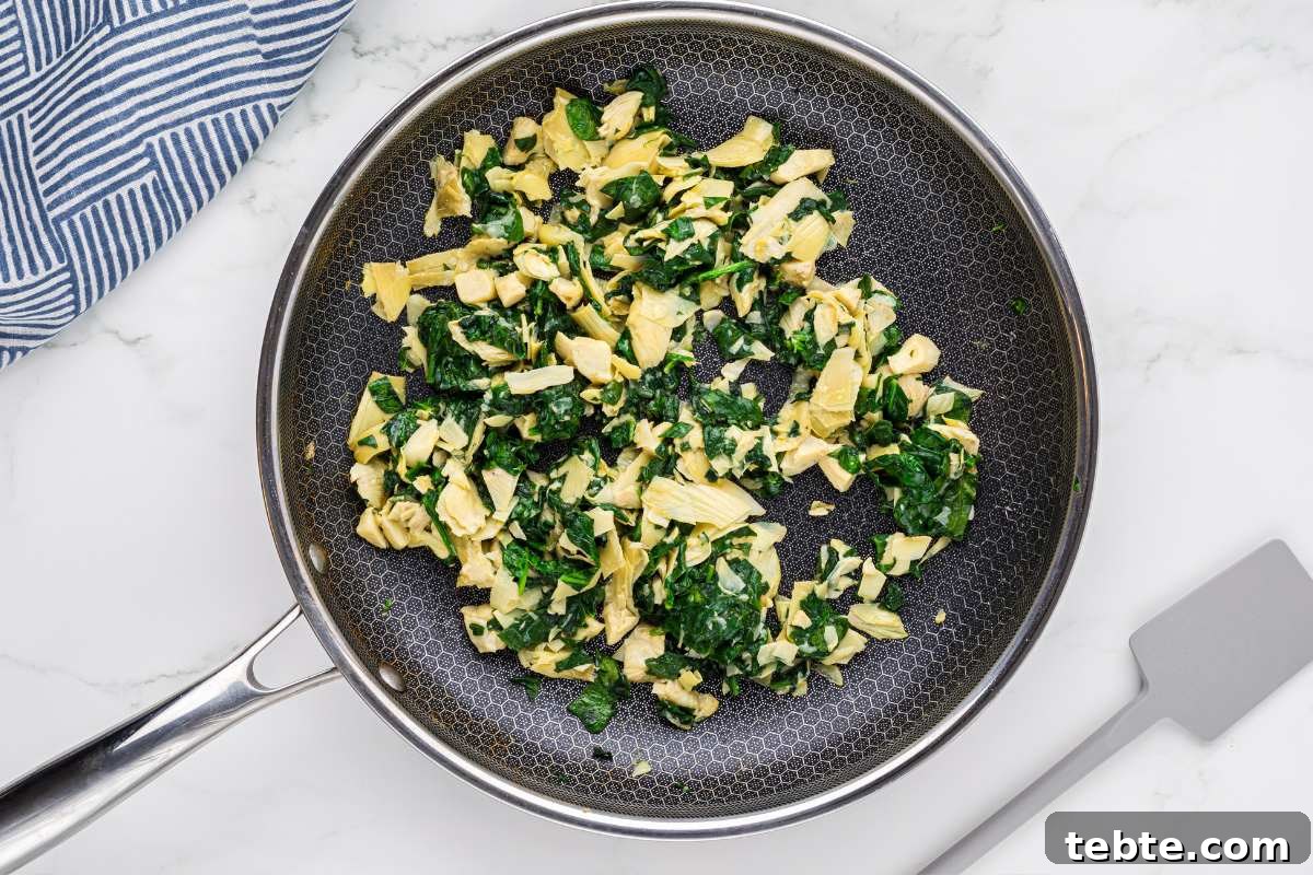 Creamy Chicken and Artichoke Sliders: Savory Party Bites 7 chopped spinach and artichoke hearts in skillet.