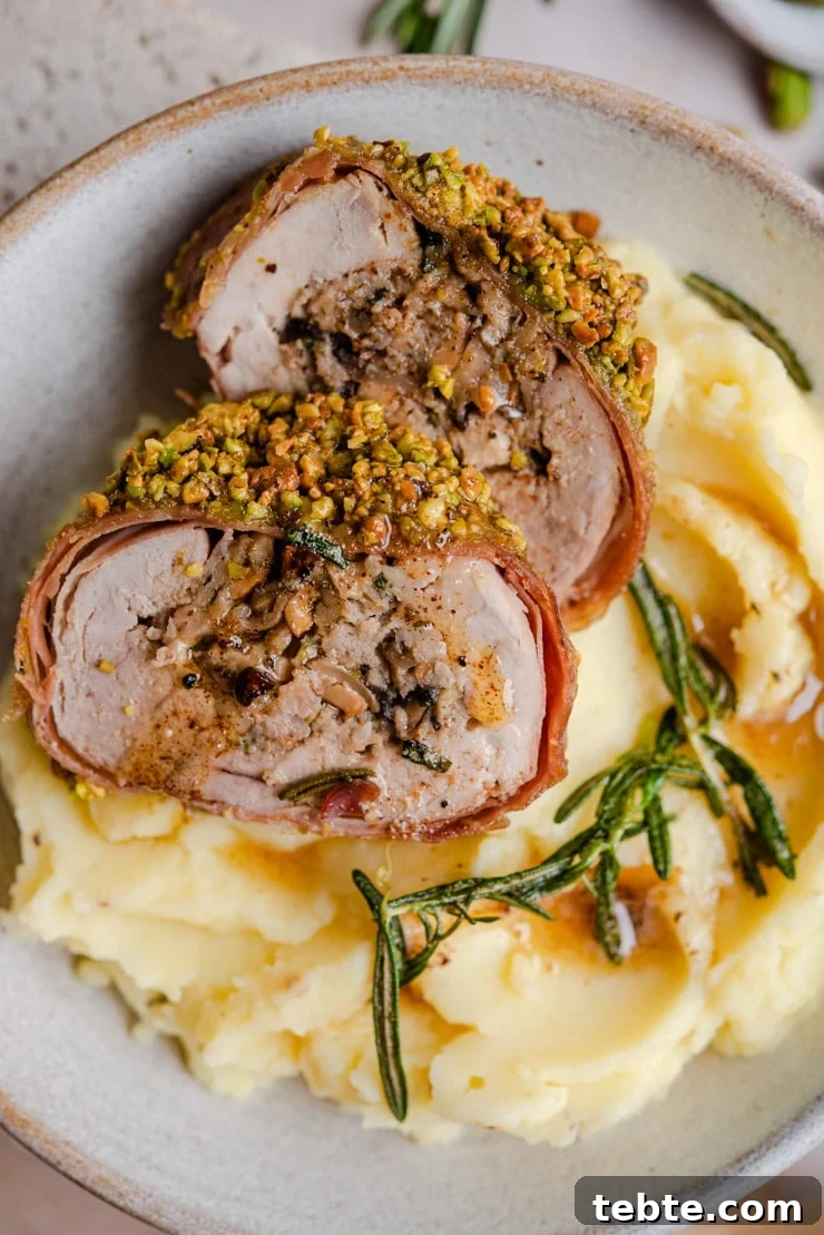 Sliced stuffed pork tenderloin on mashed potatoes A close up of stuffed pork tenderloin sitting on top of mashed potatoes