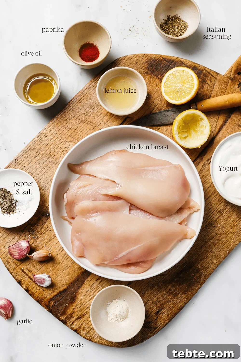 Creamy Yogurt-Marinated Chicken Breast Recipe 3 Pre-measured ingredients on a wooden cutting board with text overlay for each ingredient.