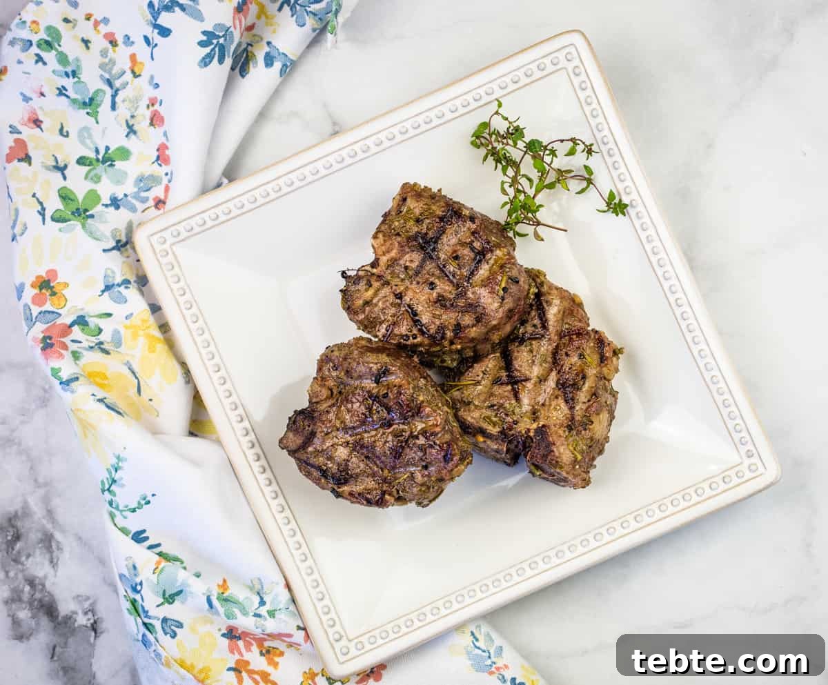 15 Easter Recipes Your Family Will Beg to Eat This Year 13 Smoked lamb chops on a white plate with a green napkin.
