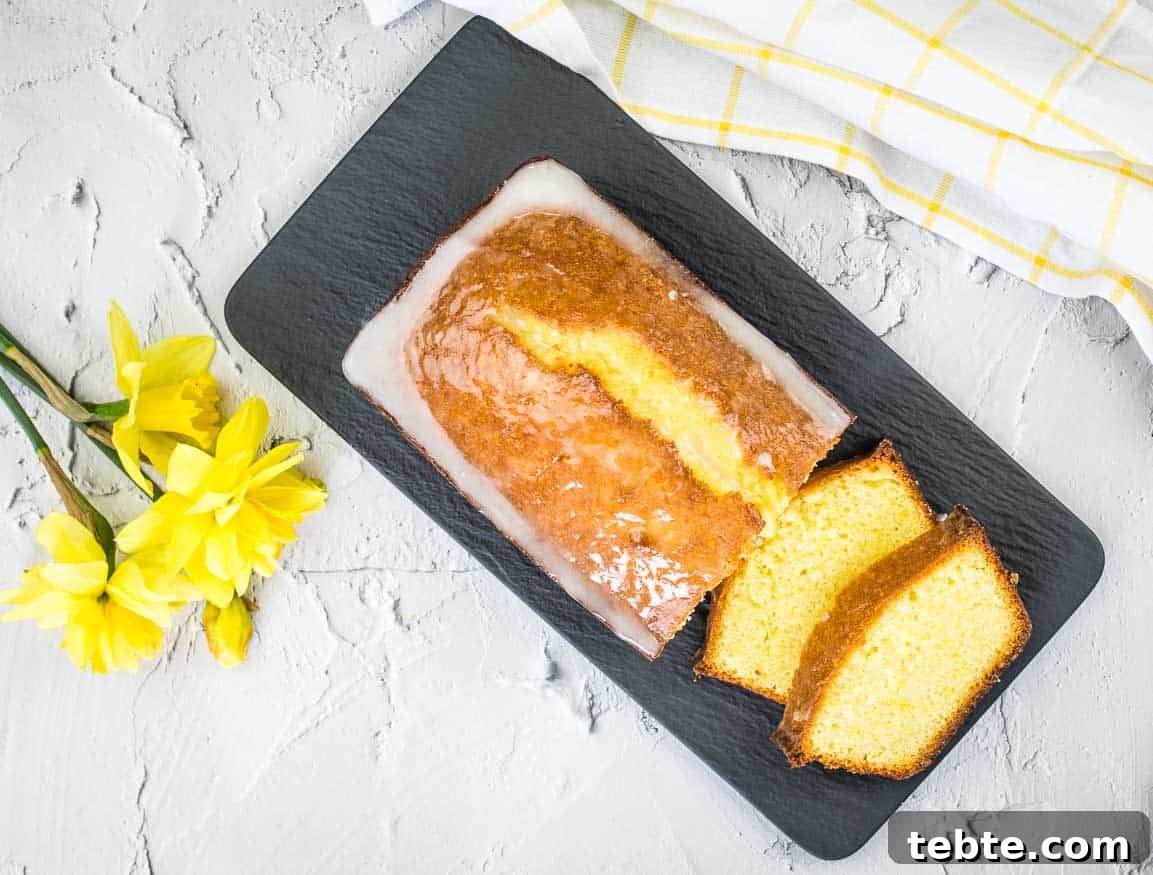 15 Easter Recipes Your Family Will Beg to Eat This Year 4 A slice of lemon pound loaf on a plate with daffodils.