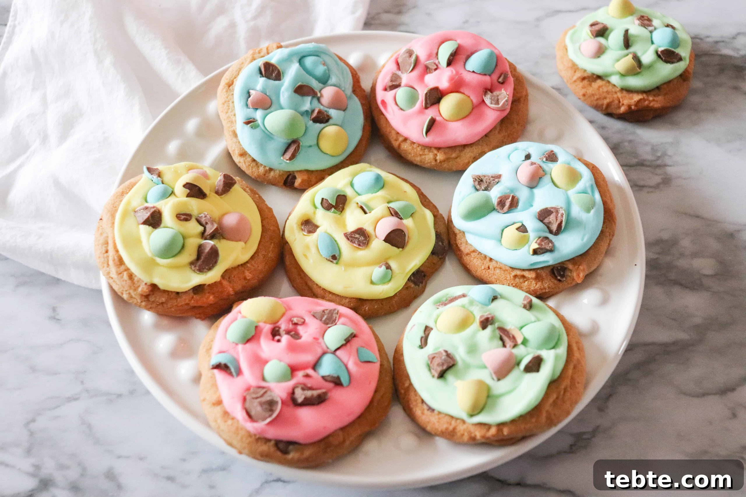 15 Easter Recipes Your Family Will Beg to Eat This Year 7 Mini egg cookies on a white plate with colorful icing.