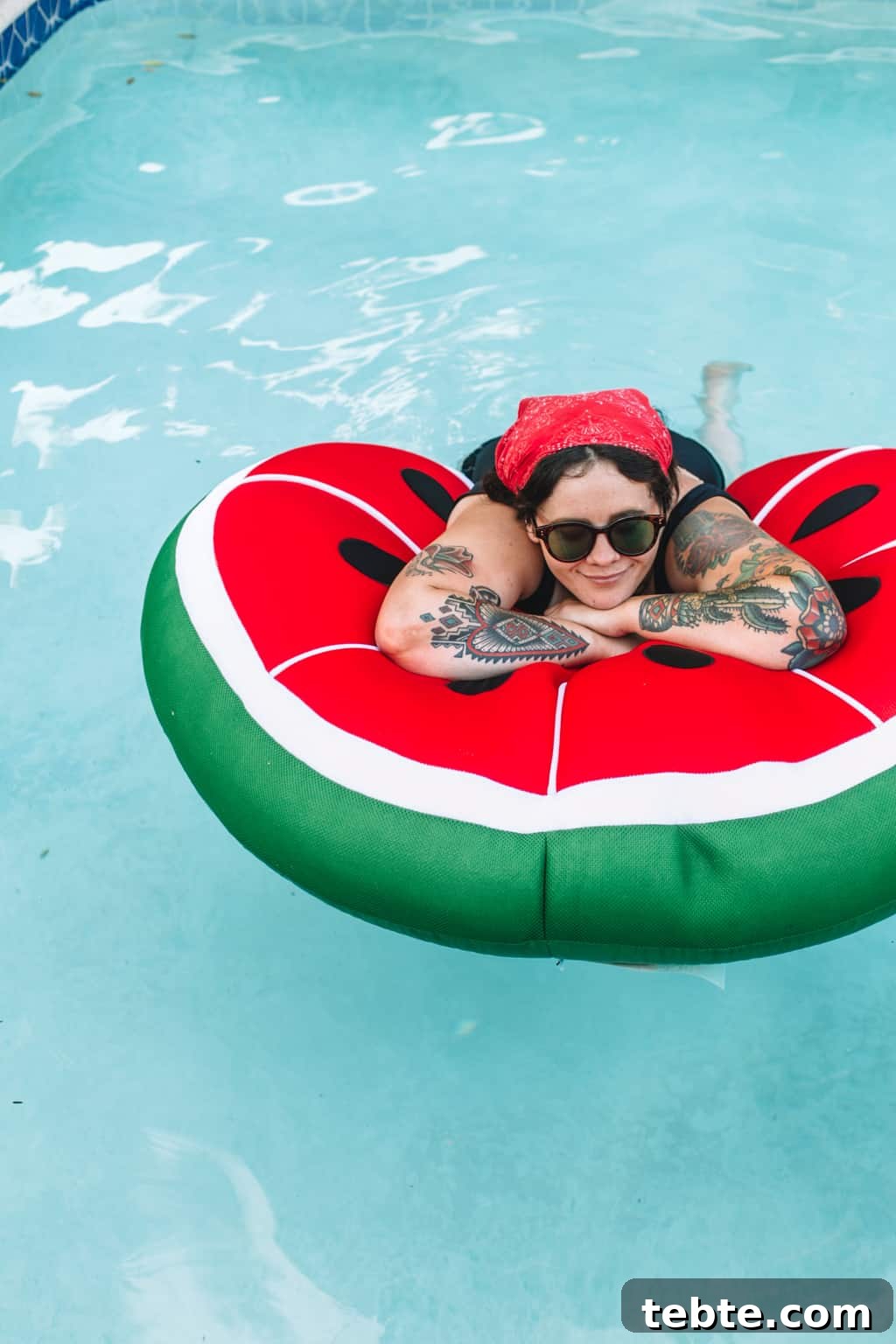 Girl in the pool sitting on a watermelon pool float.