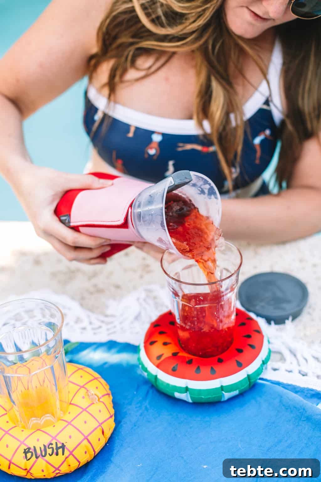 Girl in bathing suit pouring a frozen cocktail.